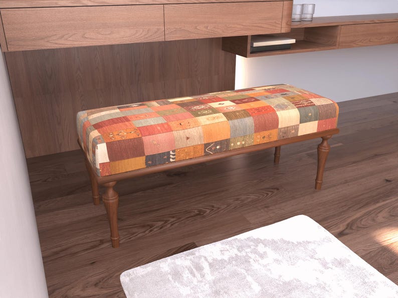 a wooden bench with a colorful, patchwork-style cushion on top, situated on a hardwood floor.