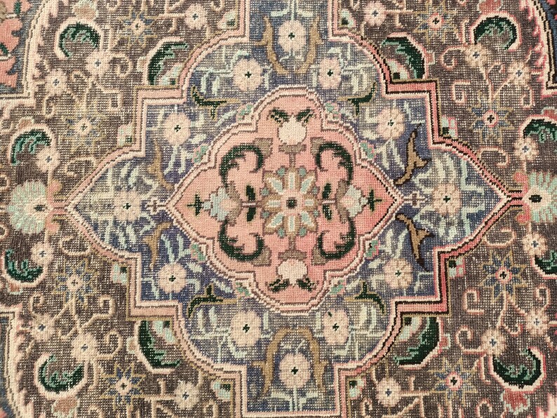 May include: A detailed close-up of a traditional rug with a central medallion design. The rug features intricate floral patterns in shades of pink, blue, green, and brown.