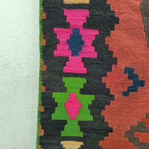 Puede incluir: Un primer plano de una alfombra tejida colorida con patrones geom&eacute;tricos en tonos de rosa, verde, azul y marr&oacute;n. La alfombra tiene un dise&ntilde;o tradicional y est&aacute; hecha de lana.