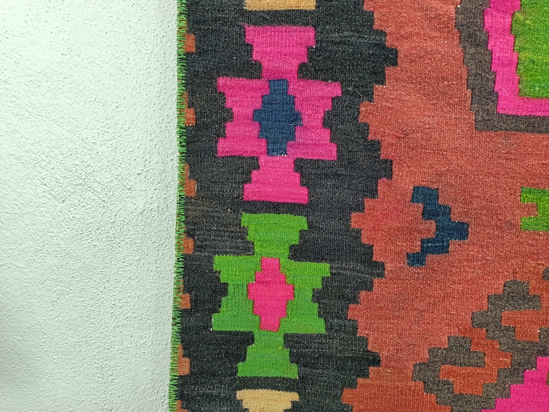 Puede incluir: Un primer plano de una alfombra tejida colorida con patrones geom&eacute;tricos en tonos de rosa, verde, azul y marr&oacute;n. La alfombra tiene un dise&ntilde;o tradicional y est&aacute; hecha de lana.