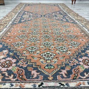 May include: A vintage rug with a floral pattern in shades of orange, pink, and blue. The rug has a central medallion and a border with a geometric design.