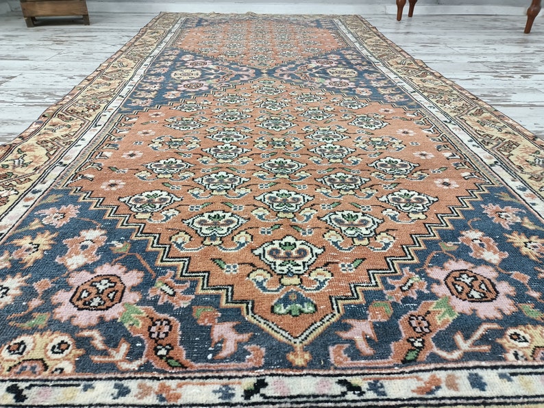 May include: A vintage rug with a floral pattern in shades of orange, pink, and blue. The rug has a central medallion and a border with a geometric design.