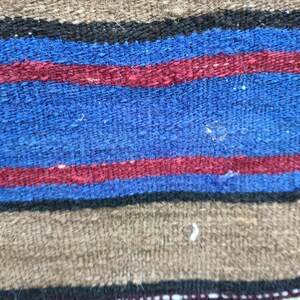 May include: Close-up of a woven fabric with alternating stripes of brown, black, blue, and red.