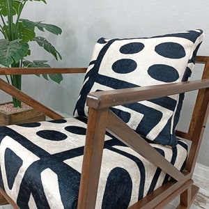 May include: A wooden rocking chair with a black and white geometric patterned cushion. The chair has a dark brown finish and a simple, classic design.