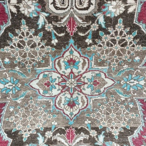 May include: A close-up of a brown, blue, and red patterned rug with intricate floral designs. The rug has a central medallion with a geometric pattern.