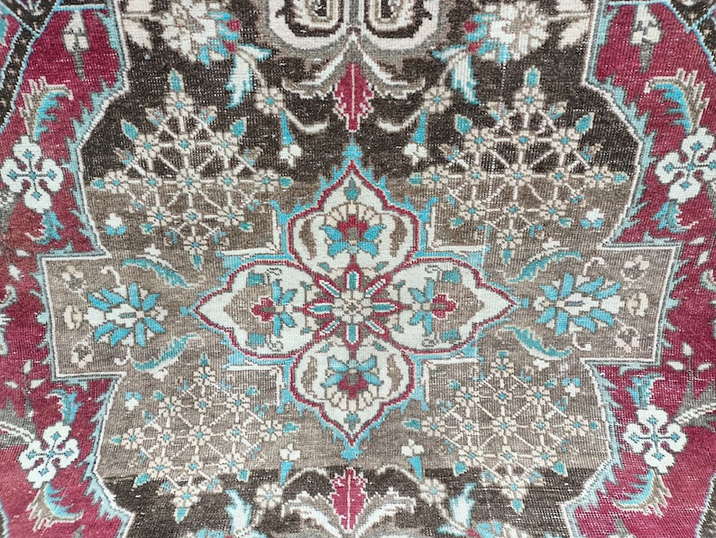 May include: A close-up of a brown, blue, and red patterned rug with intricate floral designs. The rug has a central medallion with a geometric pattern.