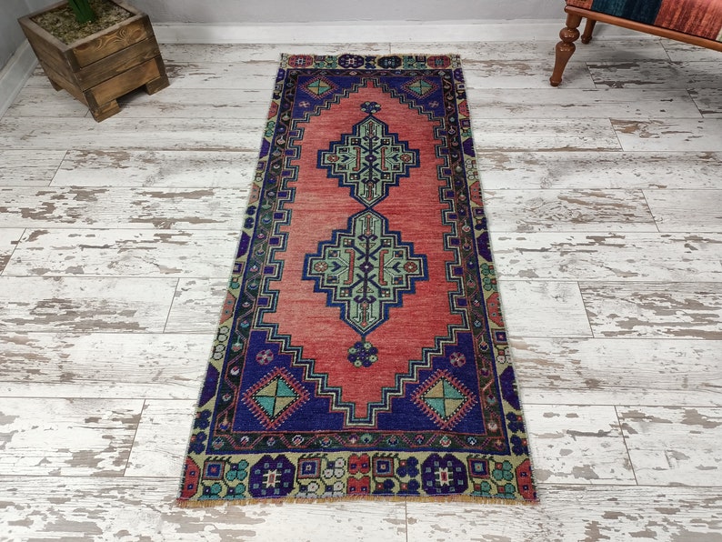 May include: A vintage runner rug with a geometric pattern in shades of red, blue, green, and beige. The rug has a distressed look and is perfect for adding a touch of bohemian style to any room.
