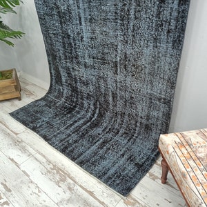 May include: A vintage style rug with a blue and black distressed pattern. The rug is made of wool and has a soft, hand-woven texture.
