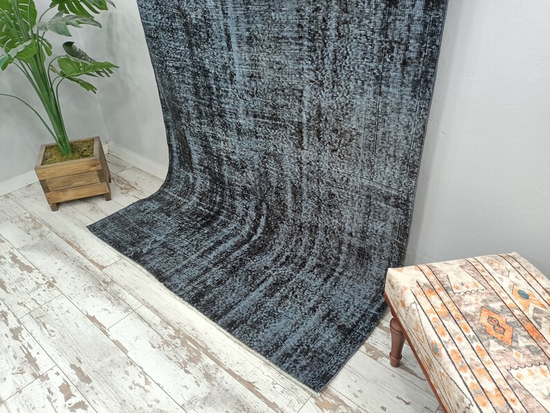 May include: A vintage style rug with a blue and black distressed pattern. The rug is made of wool and has a soft, hand-woven texture.