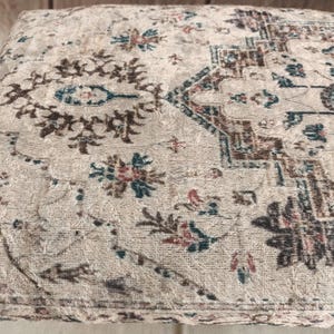 a close-up view of a decorative rug or cushion with a floral pattern.