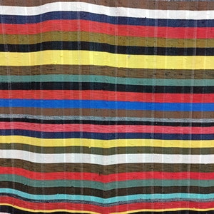 May include: A colorful striped fabric with a variety of colors, including red, yellow, blue, green, and brown. The fabric is woven with a textured pattern and has a slightly wavy appearance.