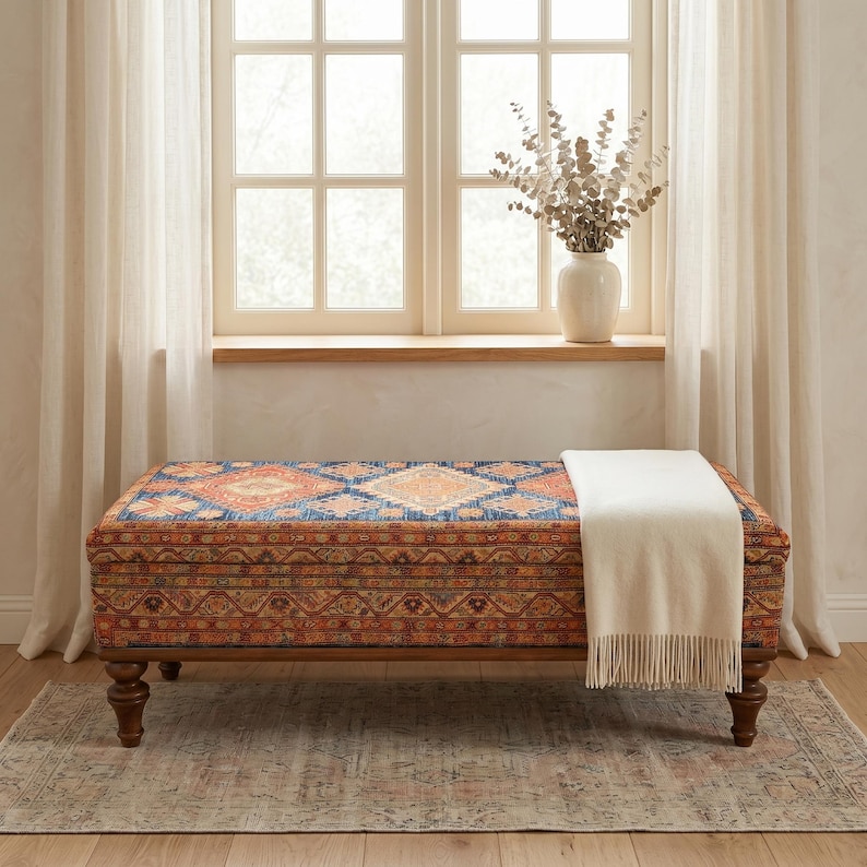 a large, colorful ottoman with a blanket draped over it, placed in front of a window with curtains.