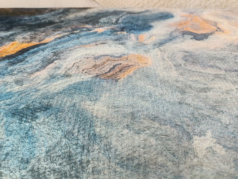 Puede incluir: Primer plano de una tela azul y blanca con un patr&oacute;n de m&aacute;rmol. La tela tiene una textura suave y peluda y est&aacute; acentuada con sutiles toques de oro.