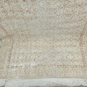 Puede incluir: Una alfombra vintage con fondo crema y un delicado patr&oacute;n intrincado en color marr&oacute;n claro. La alfombra tiene un aspecto descolorido y desgastado, lo que le da un aspecto &uacute;nico y antiguo.