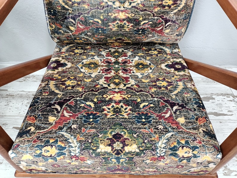 May include: A wooden armchair with a patterned fabric upholstery. The fabric features a colorful design with intricate details in shades of red, blue, green, and yellow.