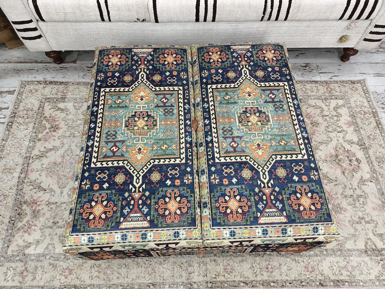 May include: Two blue and orange patterned ottoman cushions with intricate designs. The cushions are made of a soft, plush fabric and have a traditional look.