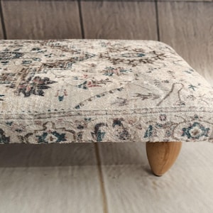 A close-up view of a decorative rug with intricate patterns and designs, placed on a wooden floor.
