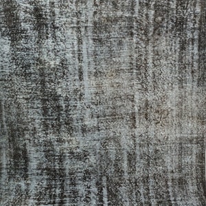 May include: A vintage rug with a distressed, faded look. The rug has a black and white color scheme with a subtle blue undertone. The rug has a textured, woven appearance.