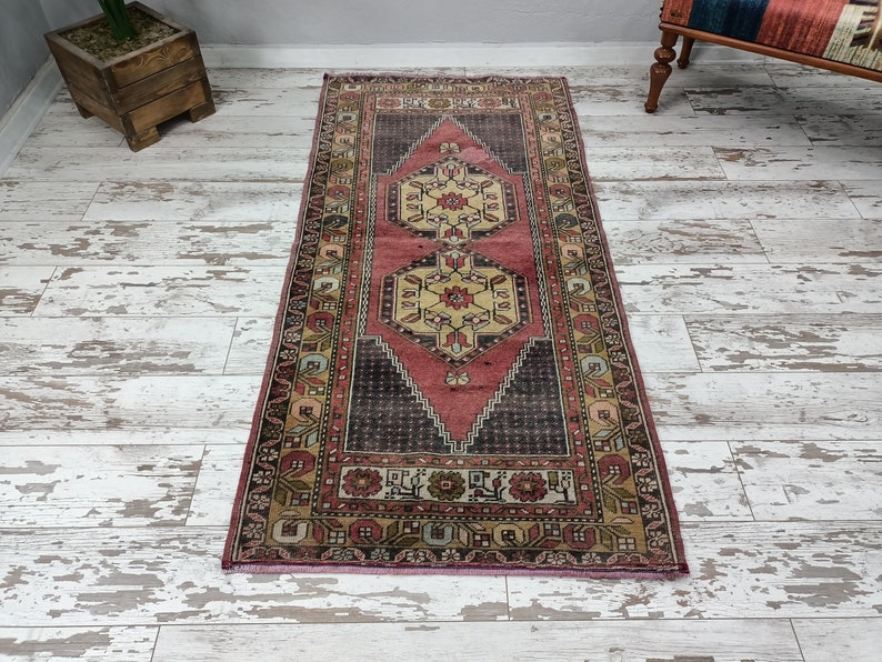 May include: A vintage runner rug with a pink, cream, and brown geometric pattern. The rug has a distressed look and is perfect for adding a touch of bohemian style to your home.