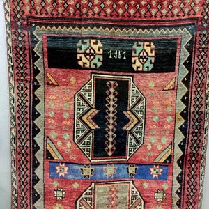 May include: A red, blue, and black patterned rug with a geometric design. The rug has a border with a repeating pattern of diamonds and squares. The rug has the number "1381" written in the center.