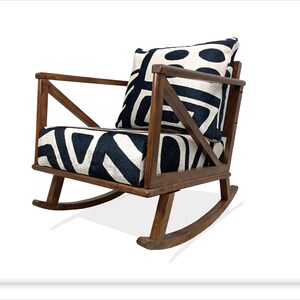 May include: A wooden rocking chair with a black and white patterned cushion and a matching pillow. The chair has a simple, modern design with a wide, comfortable seat.