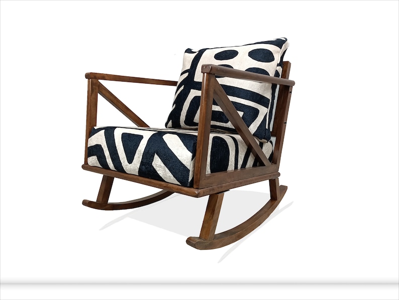 May include: A wooden rocking chair with a black and white patterned cushion and a matching pillow. The chair has a simple, modern design with a wide, comfortable seat.