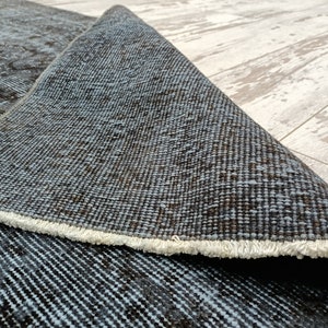 May include: Close-up of a blue and brown woven rug with a white fringe. The rug is folded in half, showing the back side of the rug.