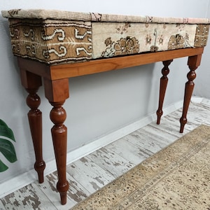 Op de afbeelding: Een houten consoletafel met een blad van patchwork stof. De tafel heeft gedraaide poten met een balvormige knop.