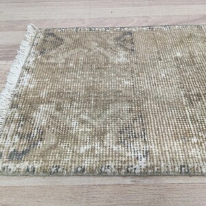 May include: A beige and brown distressed rug with a fringe border. The rug has a woven texture and a faded, vintage look.