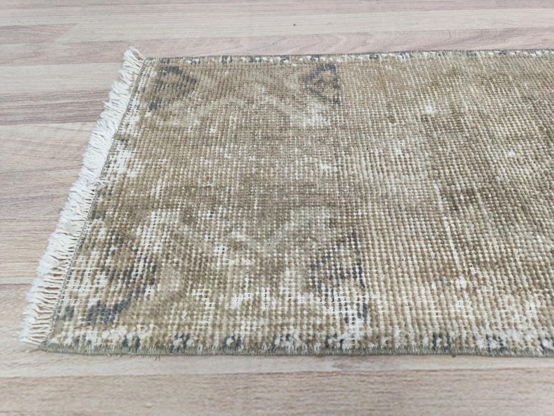 May include: A beige and brown distressed rug with a fringe border. The rug has a woven texture and a faded, vintage look.