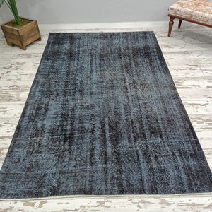 May include: A distressed vintage rug with a blue and black color scheme. The rug has a faded, worn look and a subtle pattern.