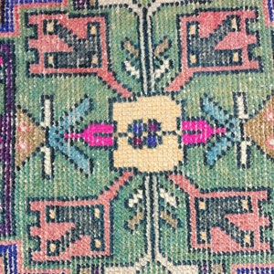 Peut inclure: Gros plan sur un tapis color&eacute; avec un motif g&eacute;om&eacute;trique. Le tapis est fait de tissu tiss&eacute; et pr&eacute;sente des nuances de rose, bleu, vert et jaune.