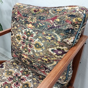 May include: A wooden armchair with a colorful patterned fabric upholstery. The fabric features a paisley design in shades of red, green, blue, and yellow.