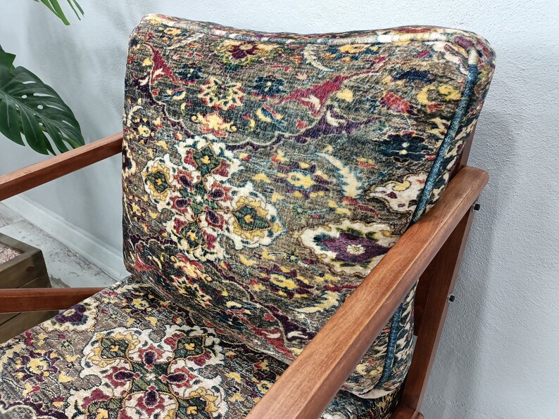 May include: A wooden armchair with a colorful patterned fabric upholstery. The fabric features a paisley design in shades of red, green, blue, and yellow.