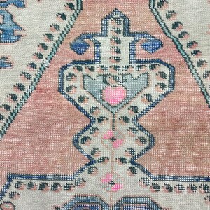 Pode incluir: Close-up de um tapete rosa e azul com detalhes intrincados. O tapete tem um design tradicional com um motivo central e padr&otilde;es repetidos.