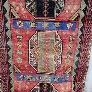 May include: A vintage red, blue, and green rug with a geometric pattern. The rug has a central medallion with a repeating pattern of stars and diamonds.