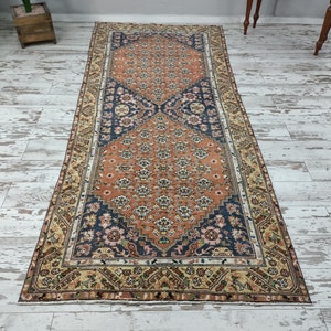 May include: A vintage runner rug with a floral pattern in shades of orange, blue, and cream. The rug has a border with a geometric design.
