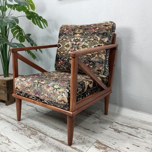 May include: A wooden armchair with a patterned fabric upholstery. The chair has a unique X-shaped design on the back and arms. The fabric is a mix of brown, green, and red colors.