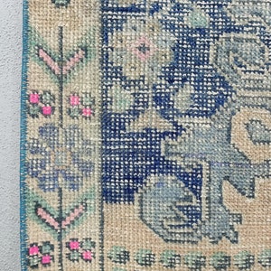 K&ouml;nnte beinhalten: Nahaufnahme eines Vintage-Teppichs mit einem blauen und wei&szlig;en Blumenmuster. Der Teppich hat einen hellbeigen Hintergrund und einen blauen Rand.