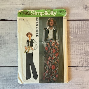 May include: A Simplicity 7783 sewing pattern envelope for size 13, featuring a Designer Fashion illustration of a person wearing a white long-sleeve shirt, a black vest, and either black wide-leg trousers or a long floral skirt with red roses.
