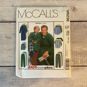 May include: A McCall's M6236 sewing pattern envelope for loungewear, featuring illustrations of robes, shirts, and pants in various colors and patterns. The cover displays a photograph of an adult and a child wearing green robes, with the text Father & Son and Easy Endless Options printed on the front.