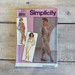 May include: A vintage Simplicity sewing pattern for a jumpsuit. The pattern envelope is pink and features illustrations of the jumpsuit in different floral and solid color fabrics. The text "Simplicity" is prominently displayed.