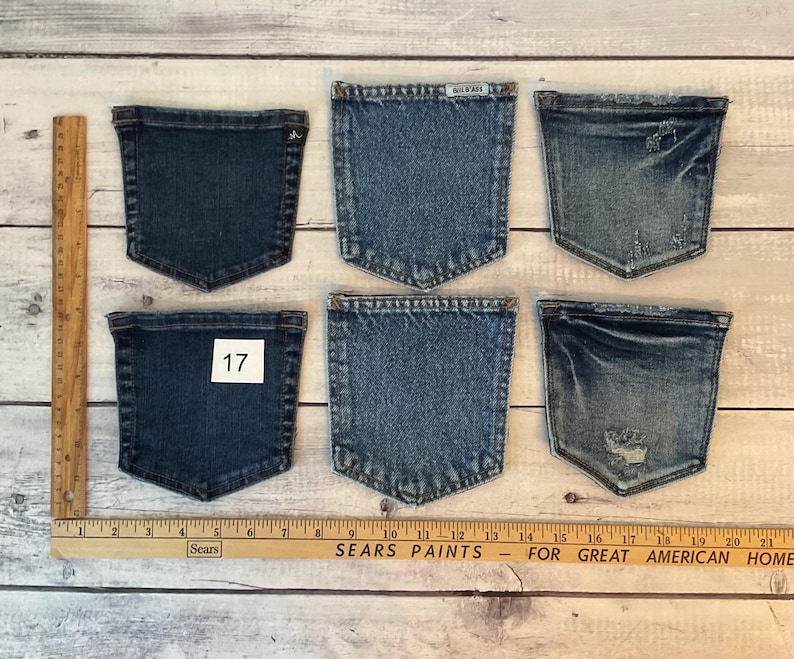 Puede incluir: Seis bolsillos de mezclilla azul dispuestos en dos filas de tres. Los bolsillos var&iacute;an en tono de azul oscuro a claro, algunos con detalles desgastados. Una regla de madera est&aacute; colocada vertical y horizontalmente, mostrando medidas en cent&iacute;metros.
