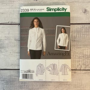 May include: A Simplicity 2339 sewing pattern envelope for a long-sleeved button-front shirt. The package features a white shirt with a ruffled placket, size range R5 14-22, and illustrations of three different shirt views labeled A, B, and C.