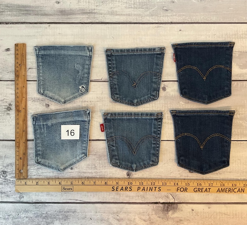 Puede incluir: Seis bolsillos de mezclilla dispuestos en dos filas de tres. Los bolsillos var&iacute;an en tonos de azul, de claro a oscuro. Una regla de madera est&aacute; colocada verticalmente a la izquierda y horizontalmente en la parte inferior, mostrando medidas en cm. El n&uacute;mero 16 es visible.