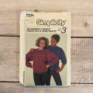 May include: Simplicity pattern envelope featuring a couple in casual attire. The envelope reads "Beginner's Choice" and "Level 3". The woman wears a burgundy sweatshirt, and the man wears a blue sweatshirt. The pattern number is 7234.