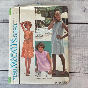 May include: A McCall's 5593 sewing pattern envelope for a dress or top. The cover features illustrations and photographs of garments, including an orange floral dress, a light blue sleeveless dress, and a light purple top. Text includes "Carefree Patterns" and "Misses' Dress or Top".