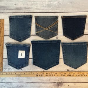 Pode incluir: Seis bolsos de ganga em v&aacute;rios tons de azul dispostos numa superf&iacute;cie, com um bolso etiquetado com o n&uacute;mero 1. Uma r&eacute;gua de madeira est&aacute; posicionada verticalmente &agrave; esquerda e horizontalmente na parte inferior, mostrando medidas em polegadas.