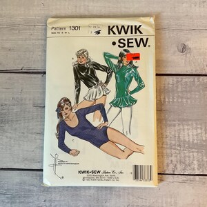 May include: A Kwik Sew pattern envelope 1301 for sizes XS-S-M-L. The front features illustrations of three long-sleeved garments: a black top with a white skirt, a green top with a peplum, and a blue leotard. Text includes Kwik Sew, 1301, and 1983.
