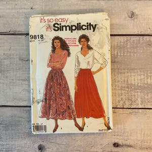 May include: A Simplicity sewing pattern envelope, number 9818, for sizes 10-20. The cover features illustrations of two outfits: a pink long-sleeved top with a patterned skirt, and a white long-sleeved top with a solid red skirt. Text includes it's so easy.